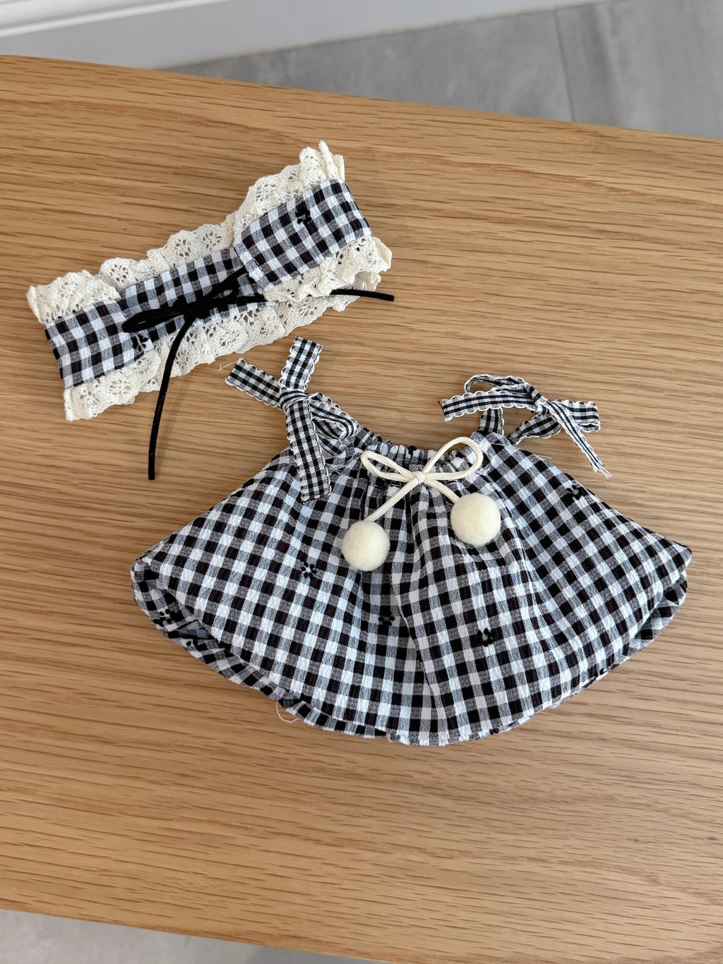 Black and white gingham dress and matching lace-trimmed bonnet for a plush toy