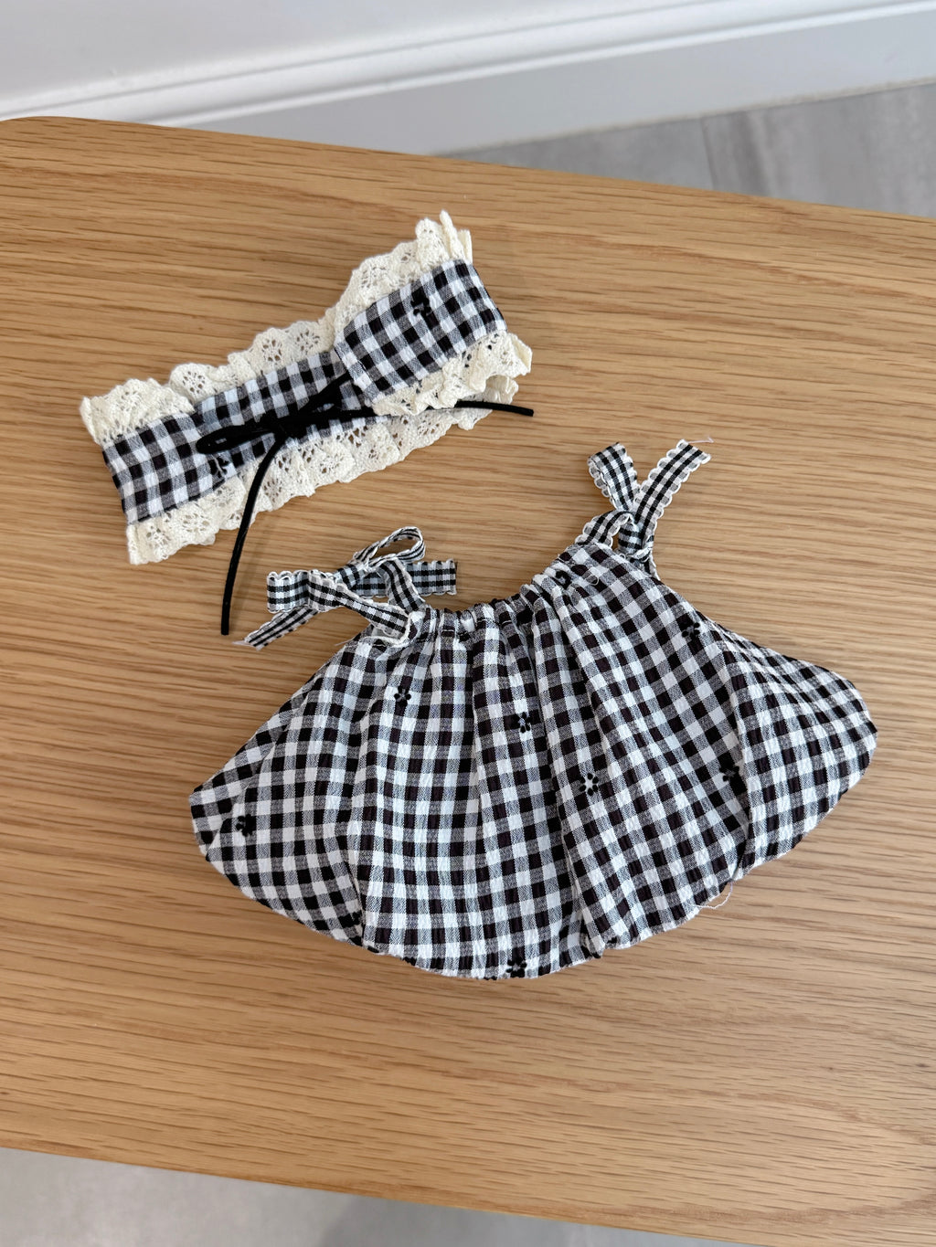 Back view of a black and white gingham dress and matching lace-trimmed bonnet for a plush toy