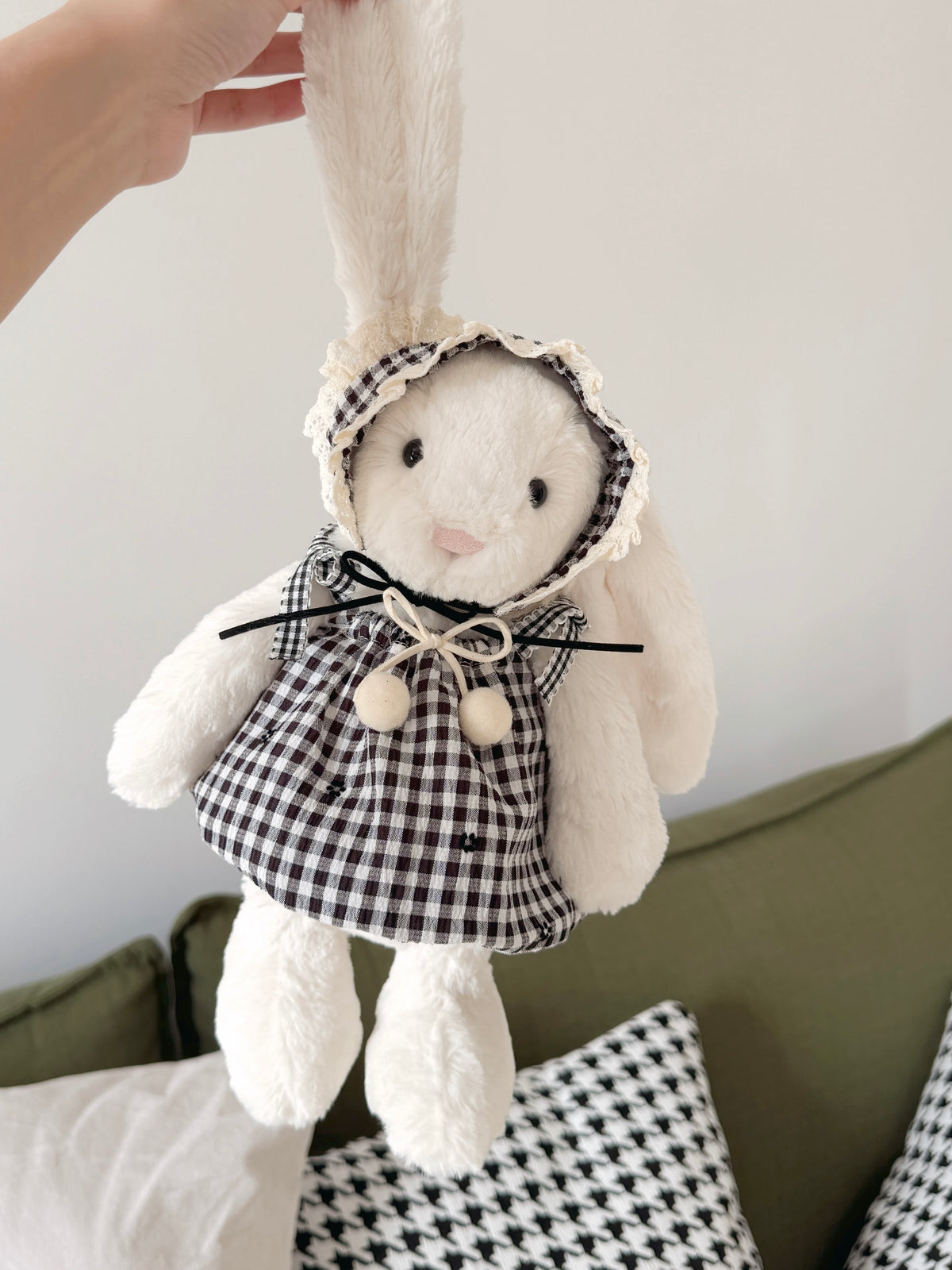 White plush bunny wearing a black and white gingham dress with matching lace-trimmed bonnet