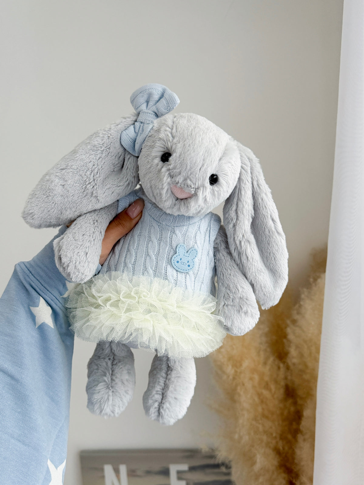 Silver plush bunny dressed in a baby blue cable knit tutu outfit with matching blue bow