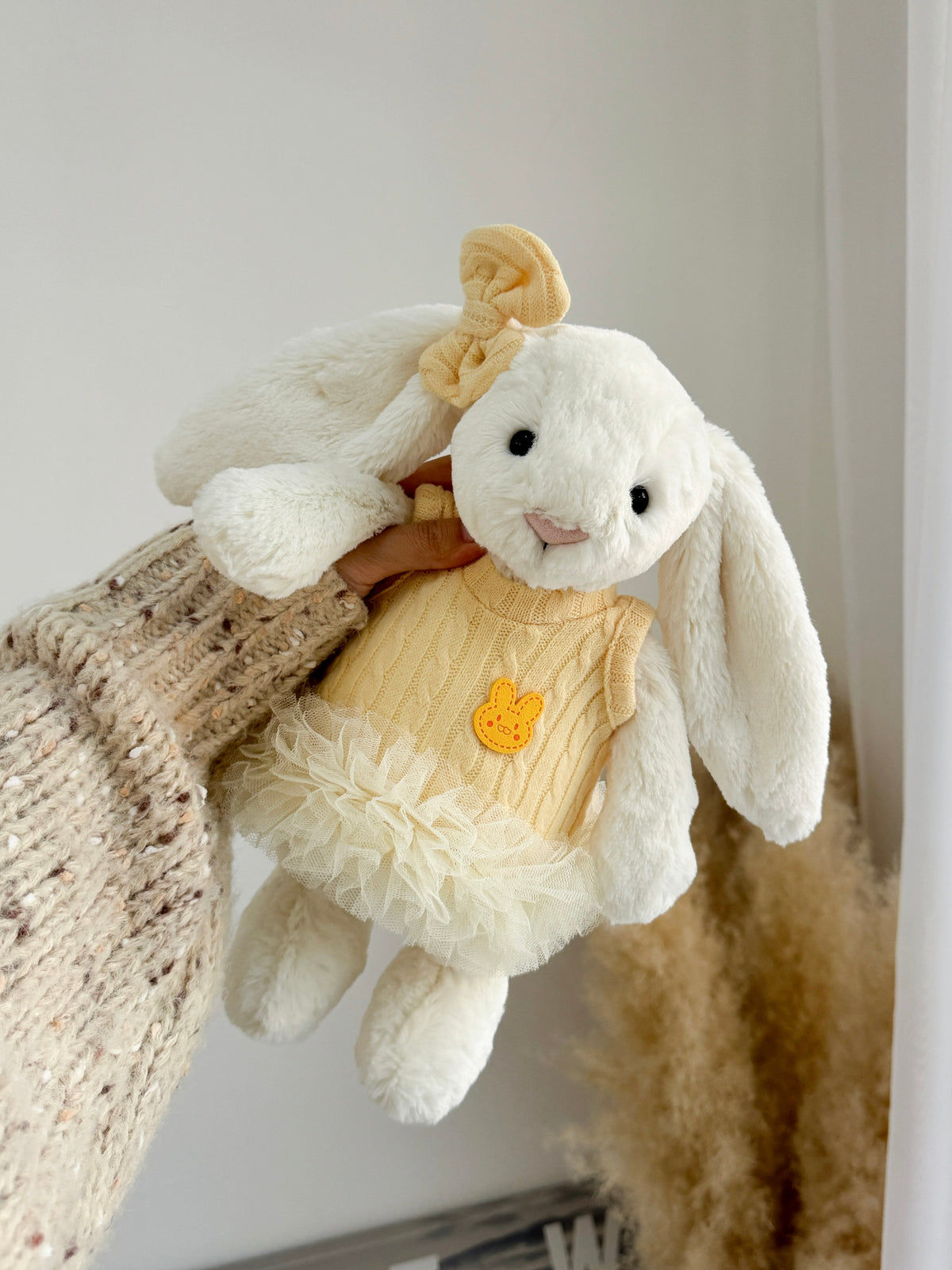 White plush bunny wearing a soft yellow cable knit tutu dress and matching bow