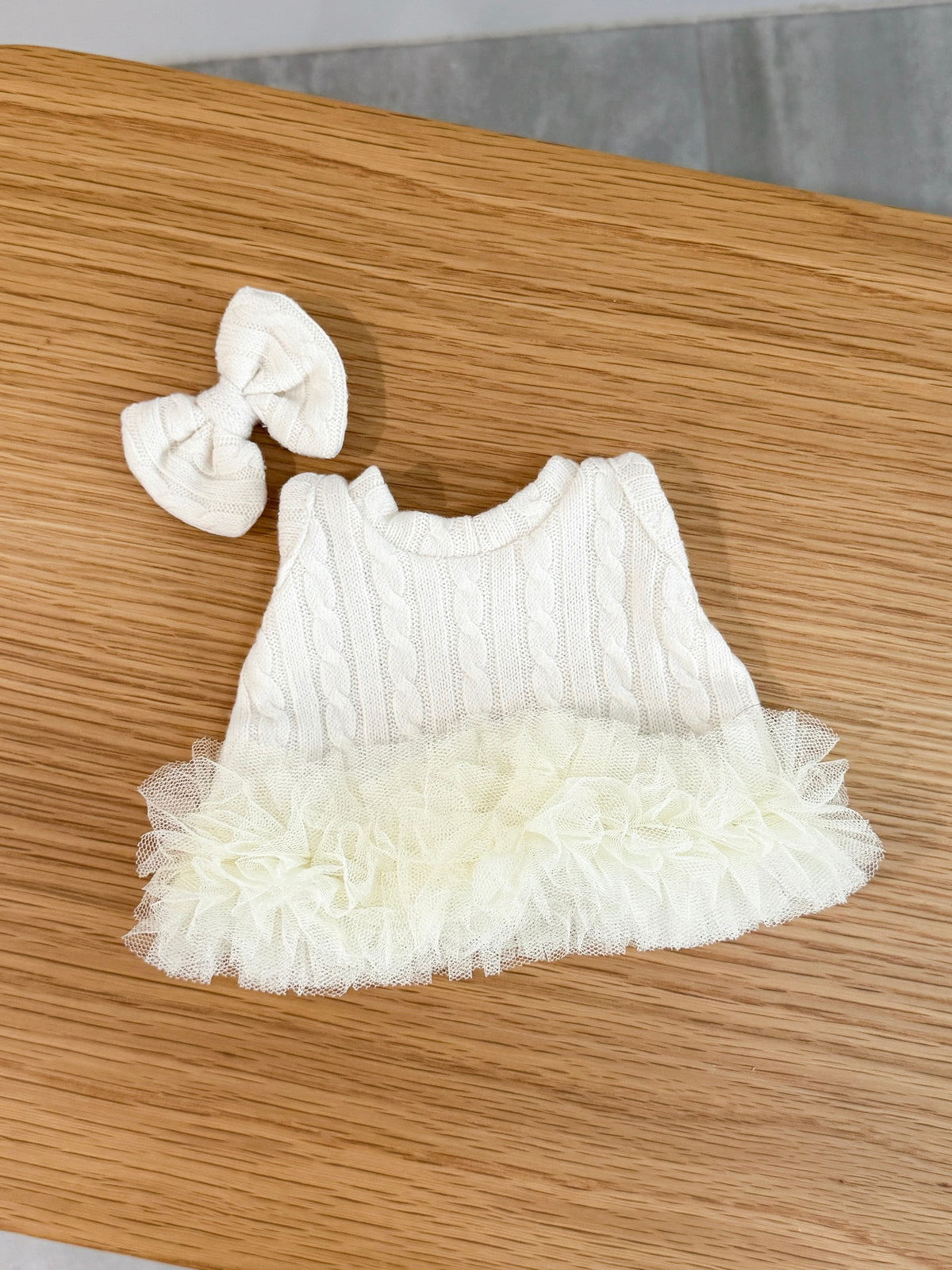 Back view of an ivory cable knit tutu dress for a plush bunny with layers of tulle and matching bow hair clip