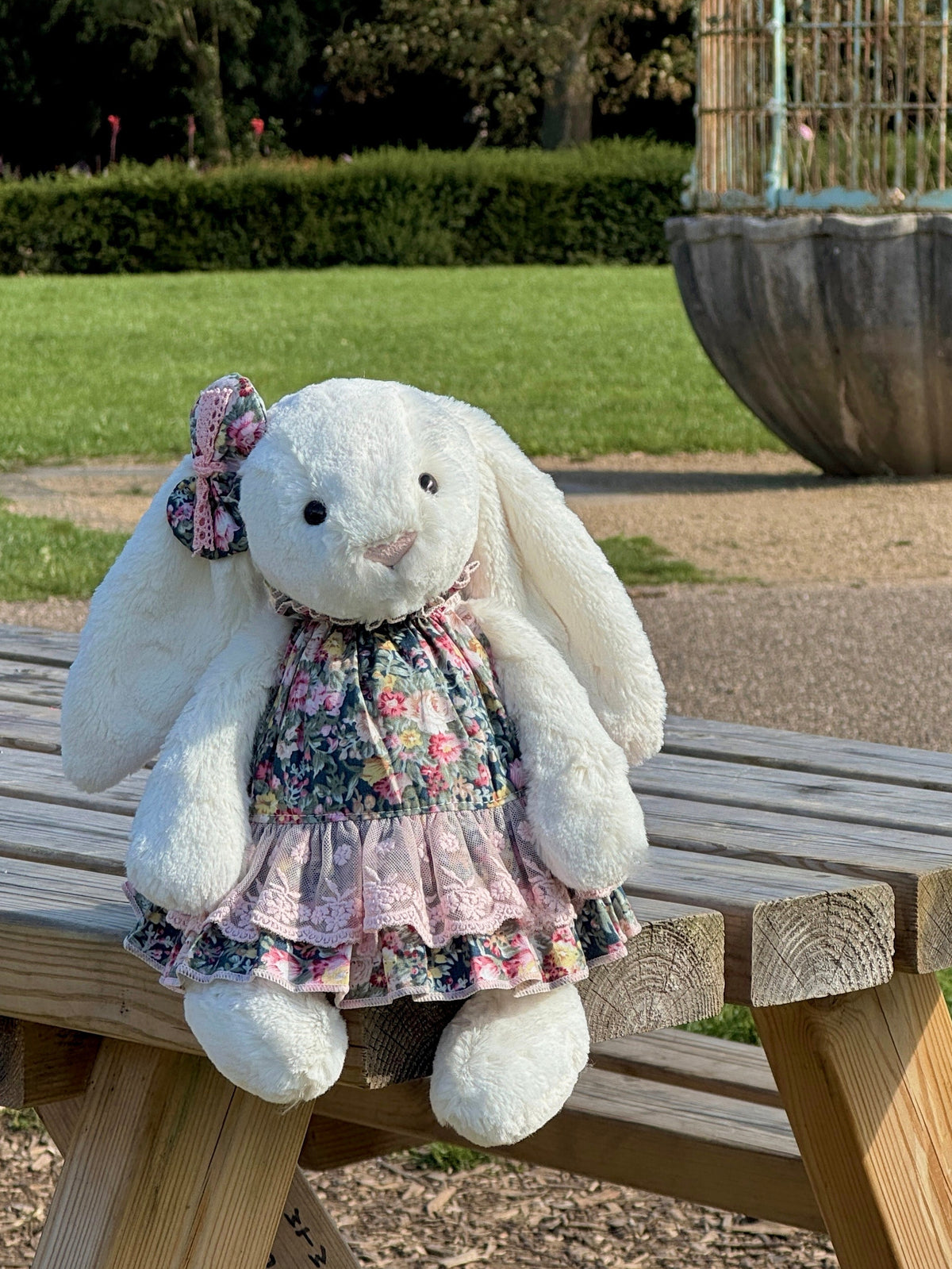 White plush bunny wearing a vintage floral tiered dress with pink embroidered lace and matching bow hair clip