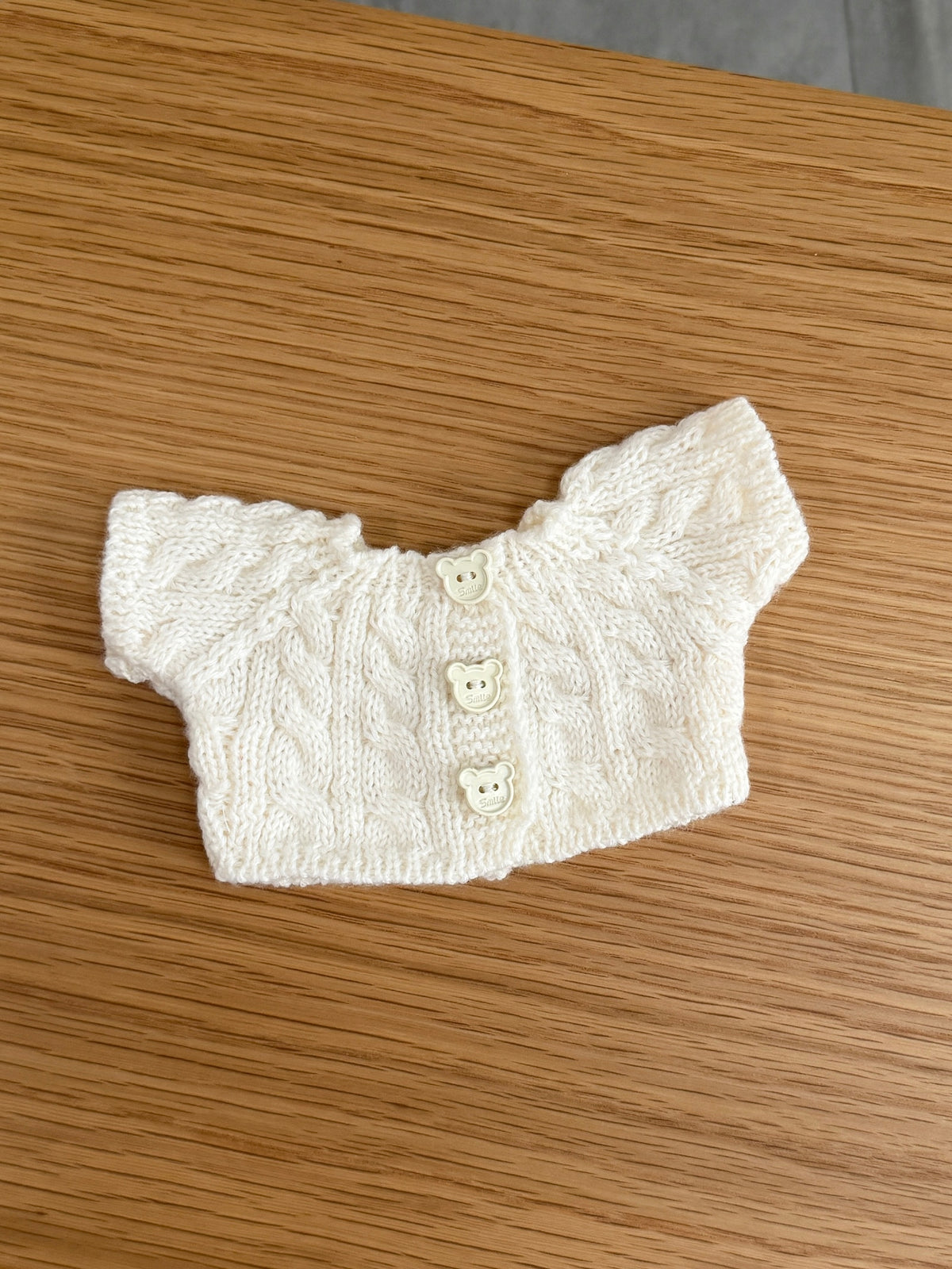Cream cable knit cardigan for a plush bunny with short sleeves and three bear-shaped buttons