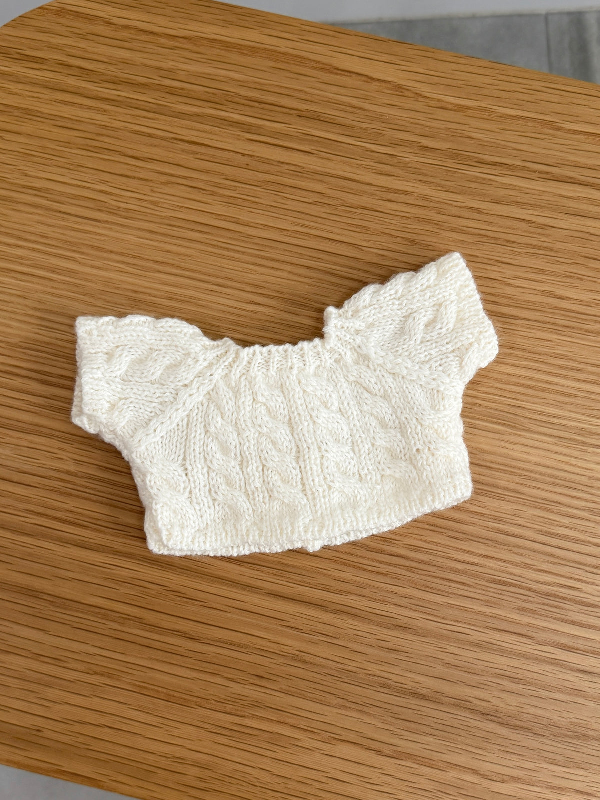 Back view of cream cable knit cardigan for a plush bunny showing the cable knit pattern