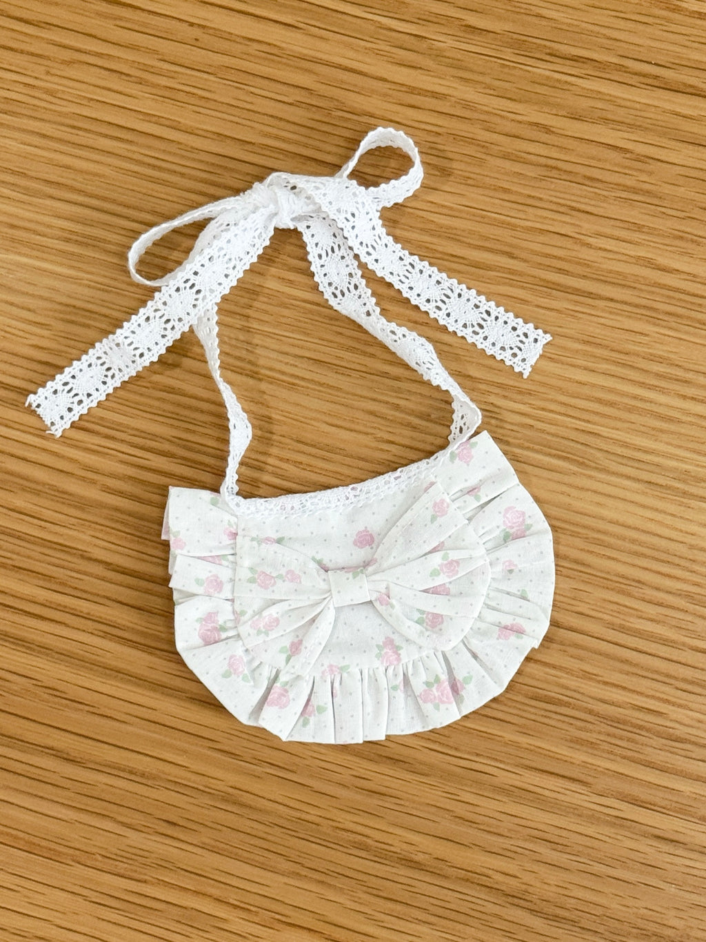 Pink rose ruffle bib for plush toys with matching floral bow and white lace tie fastening