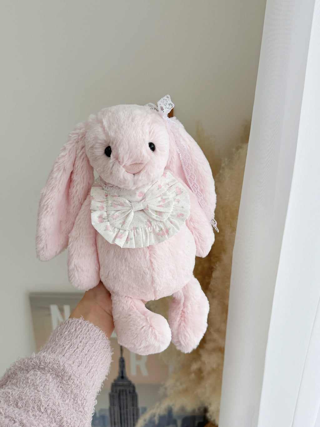 Pink plush bunny wearing a pink rose bow ruffle bib with adjustable white lace ties