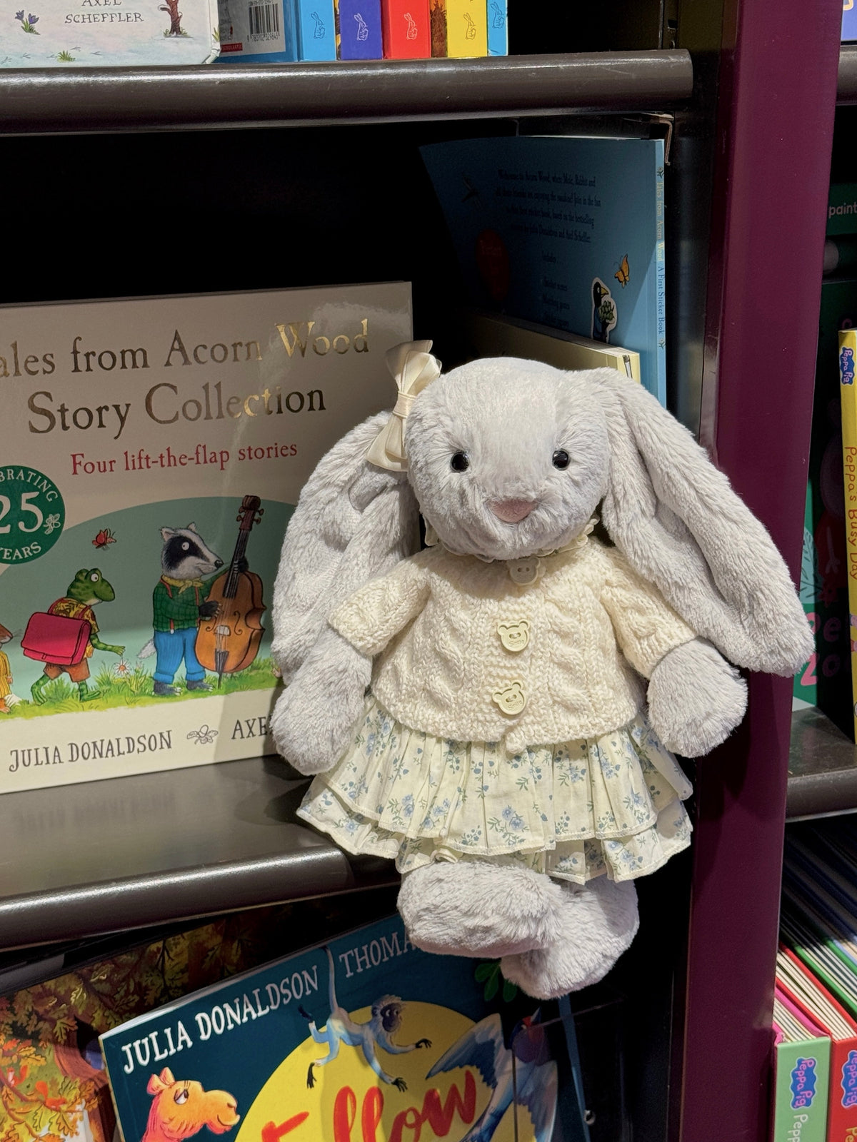 Silver plush bunny wearing a cream cable knit cardigan layered over a blue floral dress