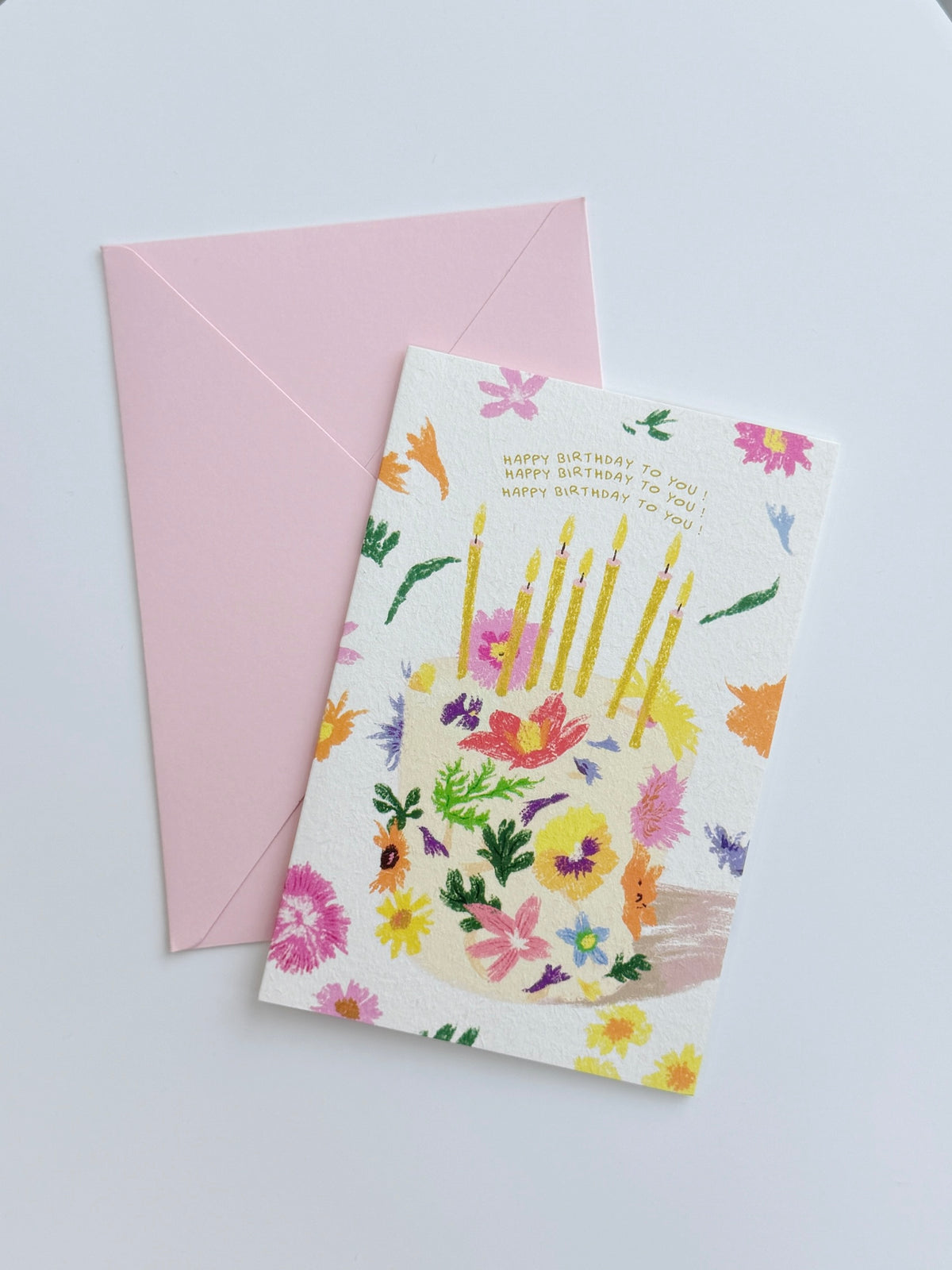 Colourful floral birthday greeting card with illustrated candles and coordinating pink envelop