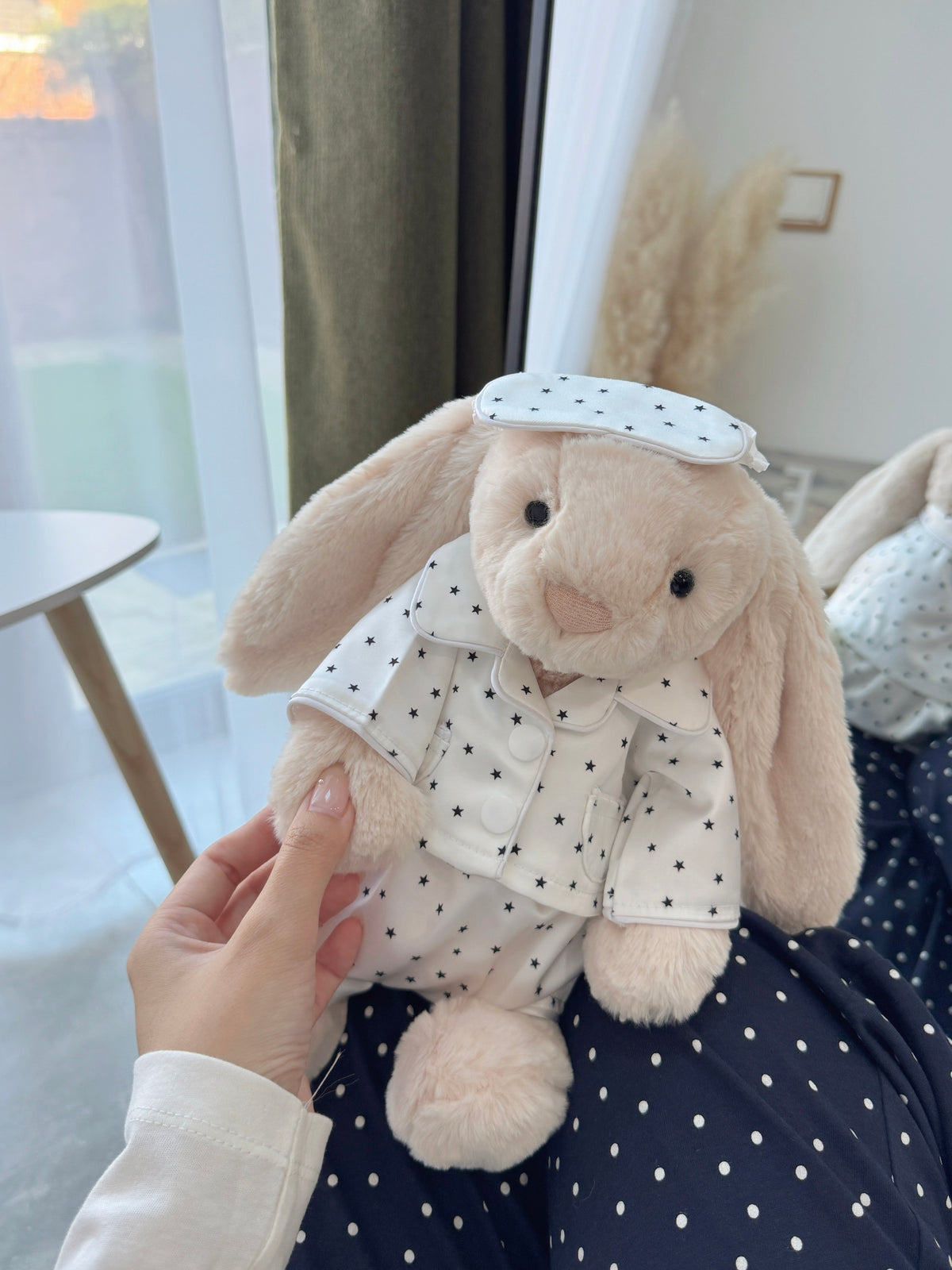 Cream plush bunny wearing a satin-style  star print pyjama top, shorts and sleep mask