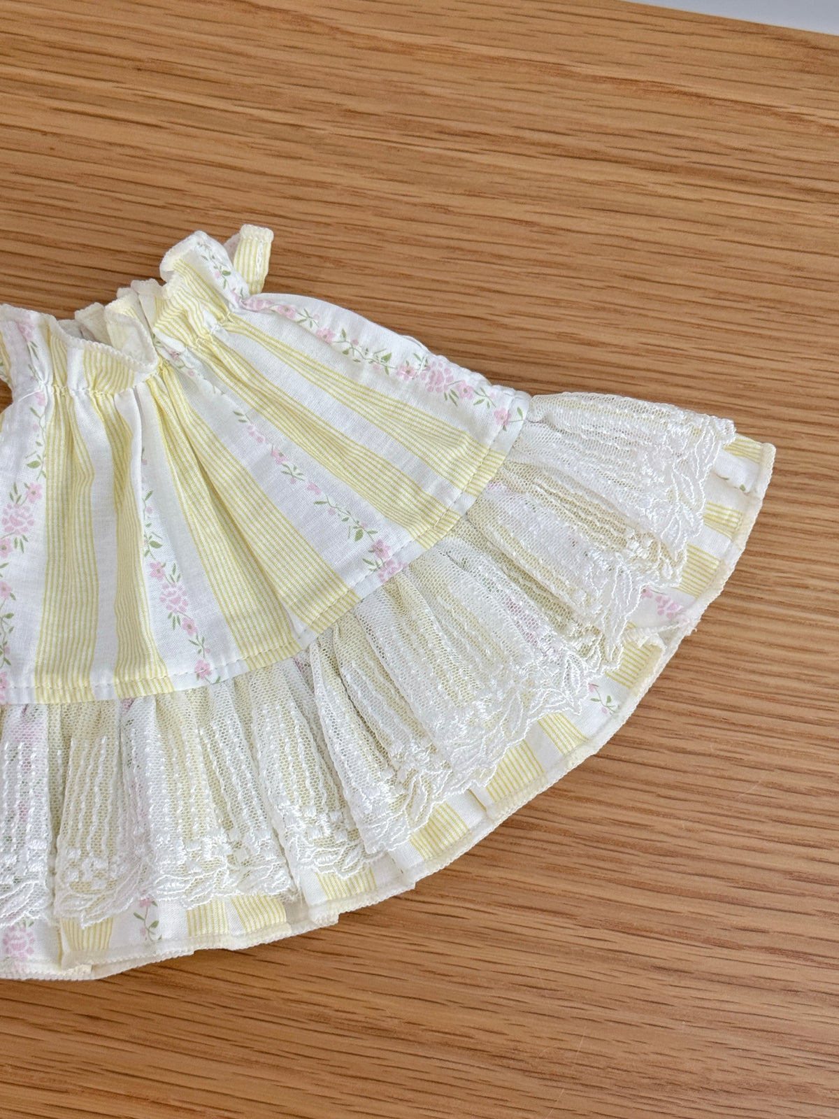 Close-up of ivory embroidered lace and floral details on yellow striped plush bunny dress