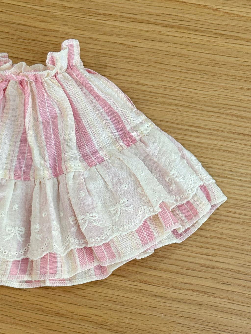 Close-up of ivory embroidered lace and bow details on pink striped plush bunny dress