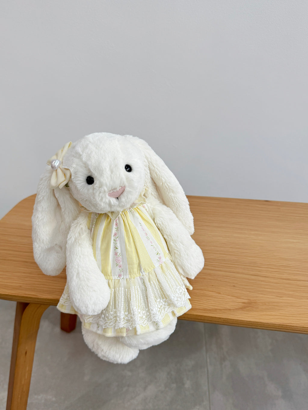 White plush bunny wearing a yellow floral striped dress with ivory embroidered lace