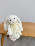 White plush bunny wearing a yellow floral striped dress with ivory embroidered lace
