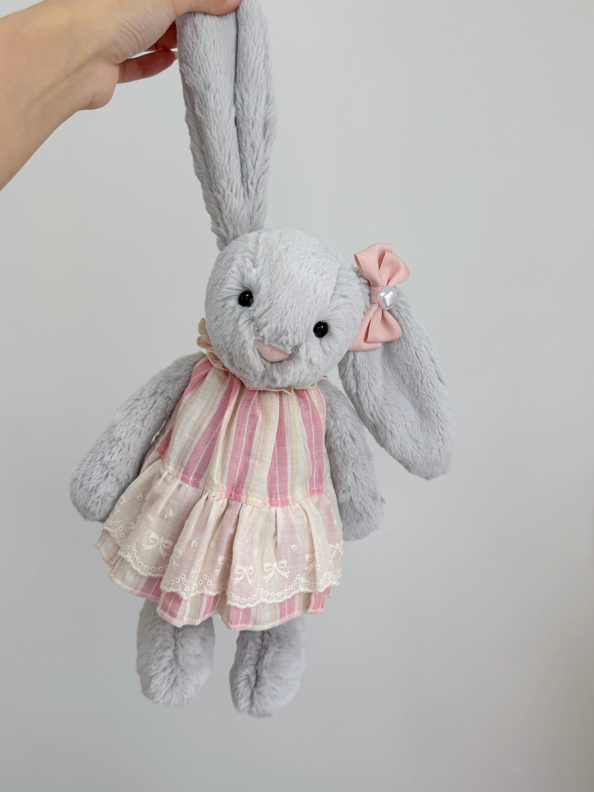 Silver plush bunny wearing a pink striped lace dress shown from the front
